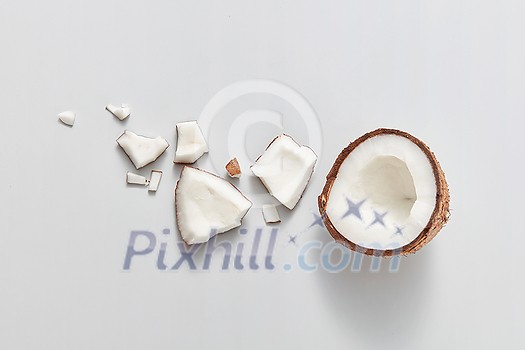 Freshly cut natural organic pieces of natural exotic coconut fruit on a light grey background with soft shadows, copy space. Vegetarian concept. Top view. Freshly cut natural organic pieces of natural exotic coconut fruit on a light grey background with soft shadows, copy space. Vegetarian concept. Top view.