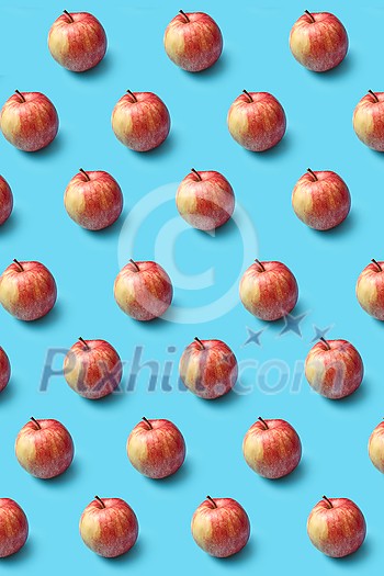 Vertical creative fruits pattern from freshly picked ripe natural organic apples on a blue background. Vegetarian concept.