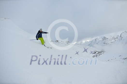 skier skiing downhill on fresh powder snow with sun and mountains in background skier skiing downhill on fresh powder snow with sun and mountains in background