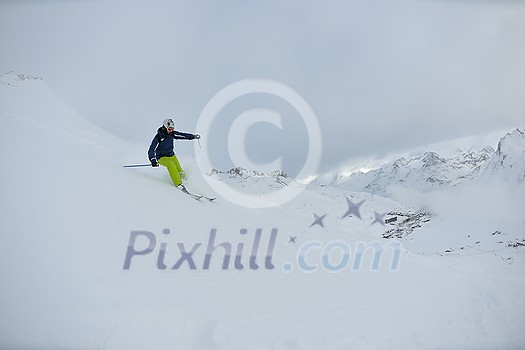 skier skiing downhill on fresh powder snow  with sun and mountains in background