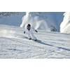 skier skiing downhill on fresh powder snow  with sun and mountains in background