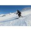 skier skiing downhill on fresh powder snow  with sun and mountains in background