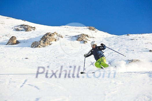 skier skiing downhill on fresh powder snow  with sun and mountains in background