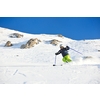 skier skiing downhill on fresh powder snow  with sun and mountains in background