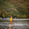 SUP Stand up paddle board concept - Pretty, young woman paddle boarding on a lovely lake in warm late afternoon light - shot from underwater