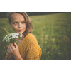 Beautiful young woman outdoors with a bouquet of wild flowers in a field, enjoying nature. Happy Woman on spring meadow