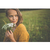 Beautiful young woman outdoors with a bouquet of wild flowers in a field, enjoying nature. Happy Woman on spring meadow