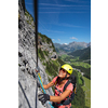 Pretty, female climber on a via ferrata - climbing on a rock in Swiss Alps