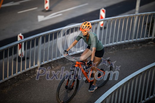 Pretty, young woman with her mountain bike going for a ride past the city limits, getting the daily cardio dose Pretty, young woman with her mountain bike going for a ride past the city limits, getting the daily cardio dose