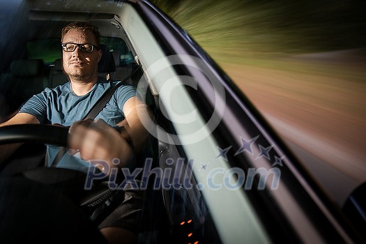 Handsome young driver driving hic car fast yet safely on the road