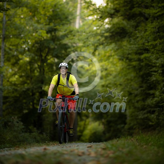 Young man with his mountain bike going for a ride past the city limits in a lovely forest, getting the daily cardio dose Young man with his mountain bike going for a ride past the city limits in a lovely forest, getting the daily cardio dose
