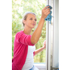 Pretty, young woman washing windows of her household. Cleaning with a detergent (shallow DOF)