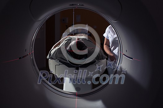 Senior man going through a Computerized Axial Tomography (CAT) Scan medical test/examination in a modern hospital (color toned image; shallow DOF) Senior man going through a Computerized Axial Tomography (CAT) Scan medical test/examination in a modern hospital (color toned image; shallow DOF)