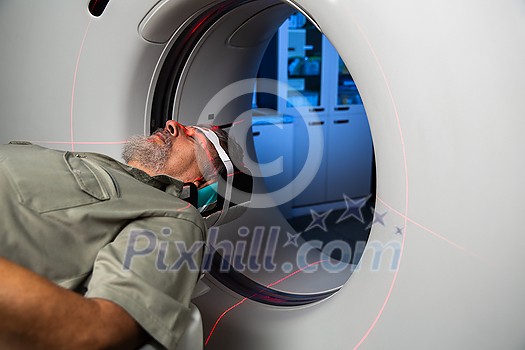 Senior man going through a Computerized Axial Tomography (CAT) Scan medical test/examination in a modern hospital (color toned image; shallow DOF) Senior man going through a Computerized Axial Tomography (CAT) Scan medical test/examination in a modern hospital (color toned image; shallow DOF)