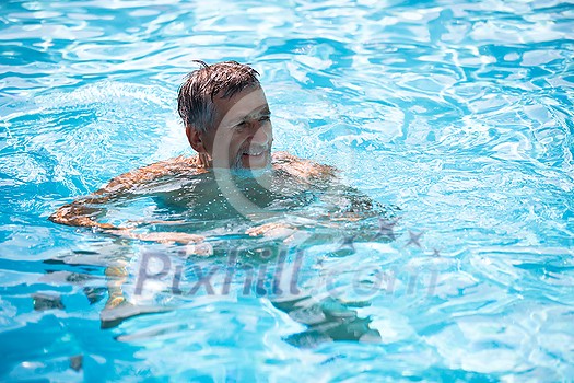 Senior man in his home swimming pool, enjoying the deserved retirement Senior man in his home swimming pool, enjoying the deserved retirement