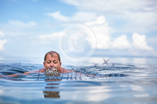 Senior man swimming in the Sea/Ocean - enjoying active retirement, having fun, taking care of himself, staying fit