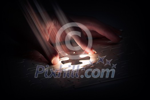 Hand connecting missing jigsaw glowing puzzle piece Hand connecting missing jigsaw glowing puzzle piece