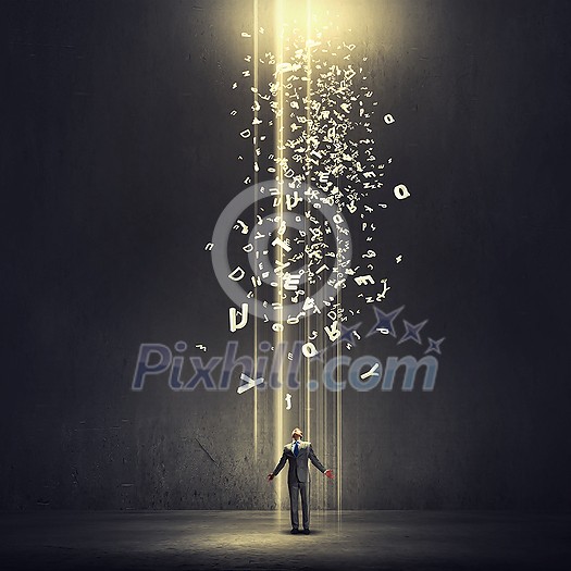 Businessman with hands spread apart standing in light coming from above Businessman with hands spread apart standing in light coming from above