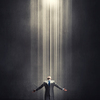 Businessman with hands spread apart standing in light coming from above