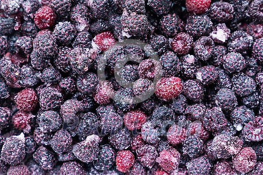 Closeup of frozen raspberries and blackberries in pile, top view