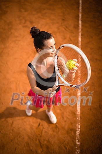 Top view of attractive young woman tennis player serving on a clay tennis court. Interesting POV shot - sporty girl during tennis training in the club Top view of attractive young woman tennis player serving on a clay tennis court. Interesting POV shot - sporty girl during tennis training in the club