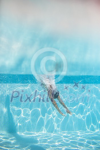 Young woman in a swimming pool performing some synchronized swimming drills Young woman in a swimming pool performing some synchronized swimming drills