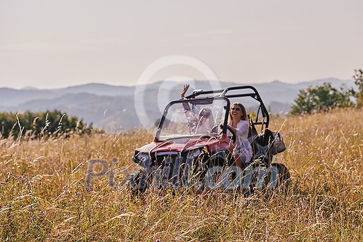 portrait of young two happy girls enjoying a beautiful sunny day while driving an off-road car in a carriage in mountain nature