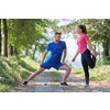 young happy couple enjoying in a healthy lifestyle warming up and stretching before jogging on a country road through the beautiful sunny forest, exercise and fitness concept