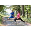 young happy couple enjoying in a healthy lifestyle warming up and stretching before jogging on a country road through the beautiful sunny forest, exercise and fitness concept