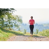 woman enjoying in a healthy lifestyle while jogging on a country road through the beautiful sunny forest, exercise and fitness concept