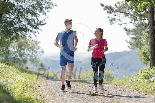 young happy couple enjoying in a healthy lifestyle while jogging on a country road through the beautiful sunny forest, exercise and fitness concept young happy couple enjoying in a healthy lifestyle while jogging on a country road through the beautiful sunny forest, exercise and fitness concept