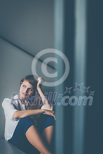 Depressed young woman sitting in a staircase, jobloss due to coronavirus pandemic, Covid-19 outbreak. Unemployment, economic crisis, financial distress concept