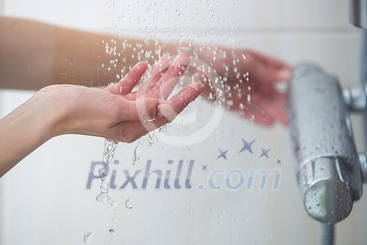 Woman taking a shower at home - female hands tryimg the temperature of water in shower Woman taking a shower at home - female hands tryimg the temperature of water in shower