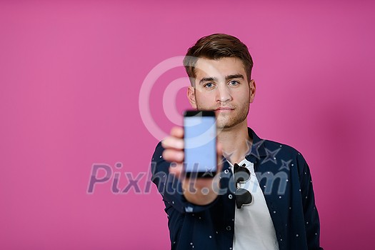 covid passport, a young man shows his code and covid passport on his cell phone while posing in front of a pink background covid passport, a young man shows his code and covid passport on his cell phone while posing in front of a pink background