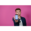 covid passport, a young man shows his code and covid passport on his cell phone while posing in front of a pink background