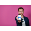 covid passport, a young man shows his code and covid passport on his cell phone while posing in front of a pink background