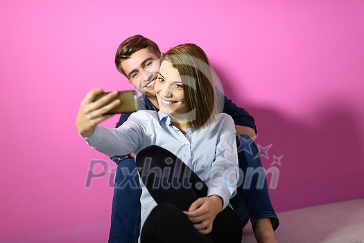 a happy young couple sitting on the floor in the house and making selfie for social network
