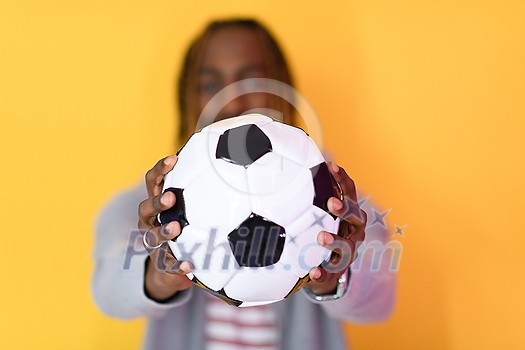 an afro man posing on a yellow background while holding a soccer ball in his hand
