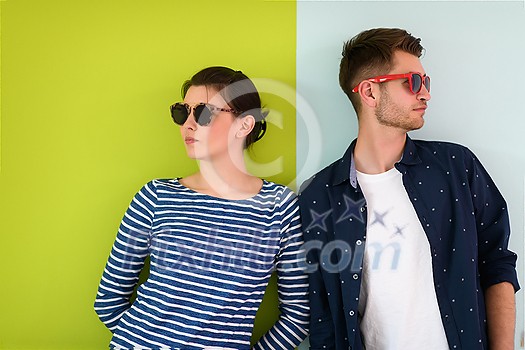 Full ready for summer! Beautiful young loving couple adjusting their sunglasses while standing against green-grey background
