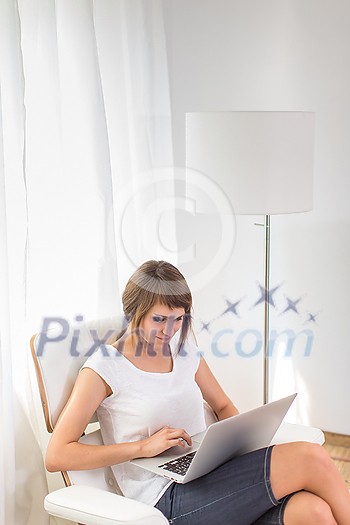 Young woman with laptop in her comfortable apartment
