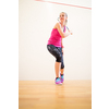 Cute young woman playing squash on a squash court, hitting the ball