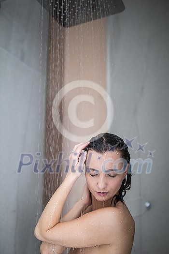 Woman taking a long hot shower washing her hair in a modern design bathroom Woman taking a long hot shower washing her hair in a modern design bathroom