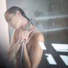 Woman taking a long hot shower washing her hair in a modern design bathroom