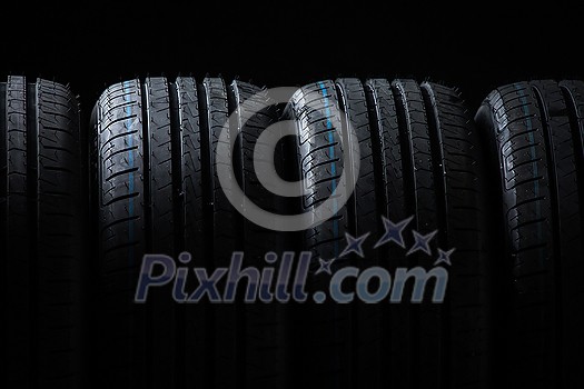 Stack of brand new high performance car tires on clean high-key white studio background