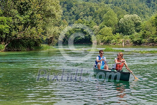 Couple adventurous explorer friends are canoeing in a wild river surrounded by the beautiful nature