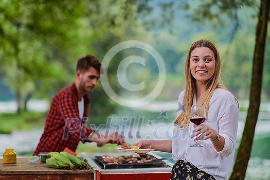 group of happy friends having picnic french dinner party outdoor during summer holiday vacation near the river at beautiful nature