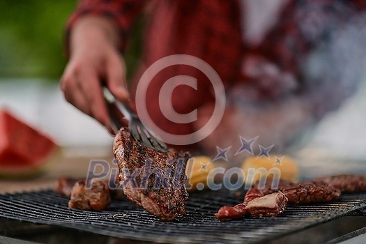 Man cooking tasty food on barbecue grill for outdoor french dinner party near the river on beautiful summer evening in nature Man cooking tasty food on barbecue grill for outdoor french dinner party near the river on beautiful summer evening in nature