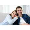 Relaxed young couple watching tv at home in bright living room
