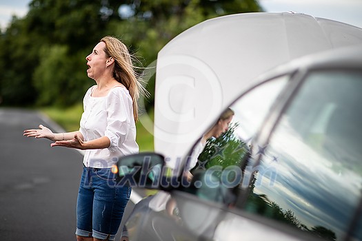 Pretty middle aged woman having car troubles - broken down car on the side of the road, calling the insurance company for assistance