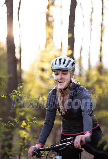 Pretty, young woman with her mountain bike going for a ride past the city limits, getting her dose of daily cardio Pretty, young woman with her mountain bike going for a ride past the city limits, getting her dose of daily cardio